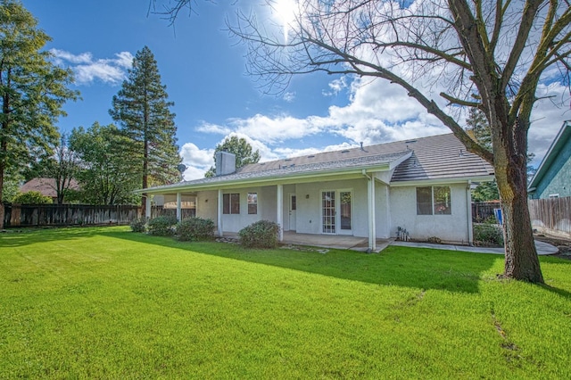 view of front facade featuring a front yard, fence, a chimney, and stucco siding