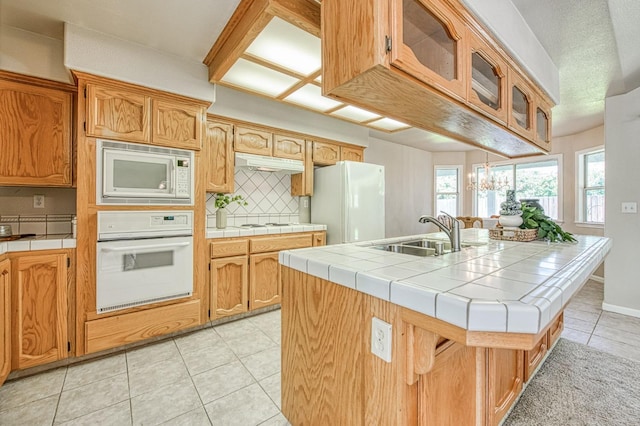 kitchen with tile countertops, decorative backsplash, a sink, white appliances, and under cabinet range hood