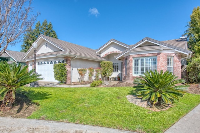 ranch-style home featuring brick siding, stucco siding, an attached garage, a tiled roof, and a front lawn