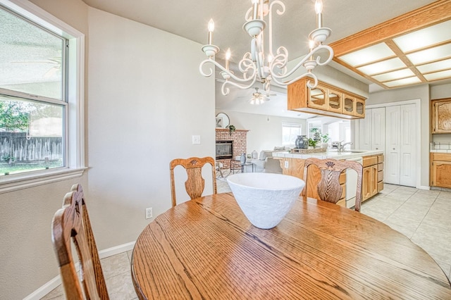 dining area featuring light tile patterned floors, a fireplace, baseboards, and a notable chandelier