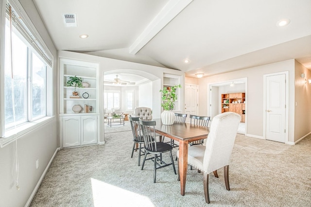 dining space featuring arched walkways, visible vents, lofted ceiling with beams, light carpet, and baseboards