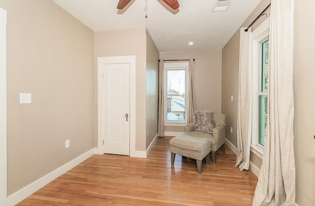 sitting room with light wood-style floors, visible vents, baseboards, and a ceiling fan