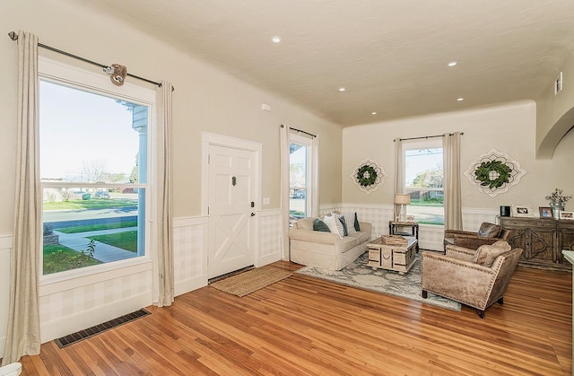 living room with recessed lighting, light wood-style flooring, visible vents, and wainscoting