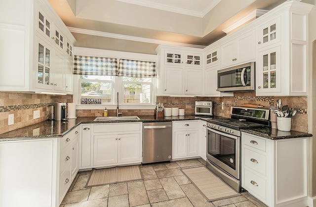 kitchen with tasteful backsplash, stainless steel appliances, crown molding, white cabinetry, and a sink