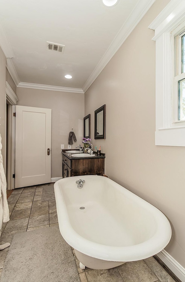 bathroom featuring a freestanding tub, vanity, visible vents, baseboards, and ornamental molding