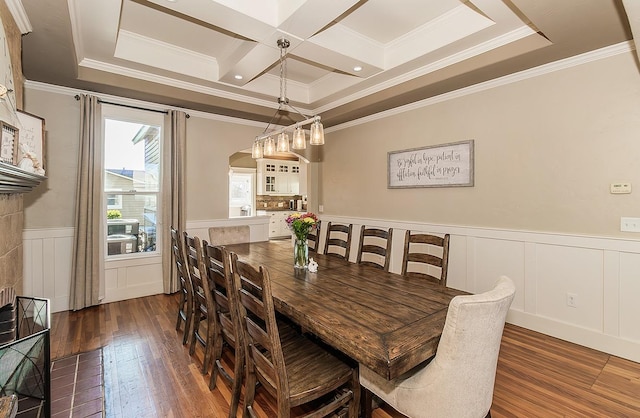 dining area with arched walkways, coffered ceiling, hardwood / wood-style flooring, a wainscoted wall, and beamed ceiling