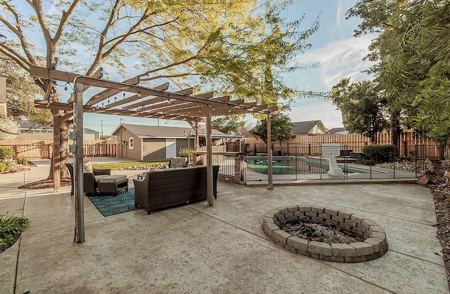 view of patio featuring an outbuilding, a fenced backyard, a fire pit, a fenced in pool, and a pergola