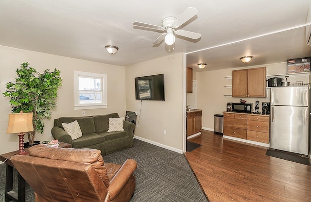 living area with a ceiling fan, dark wood-style flooring, and baseboards