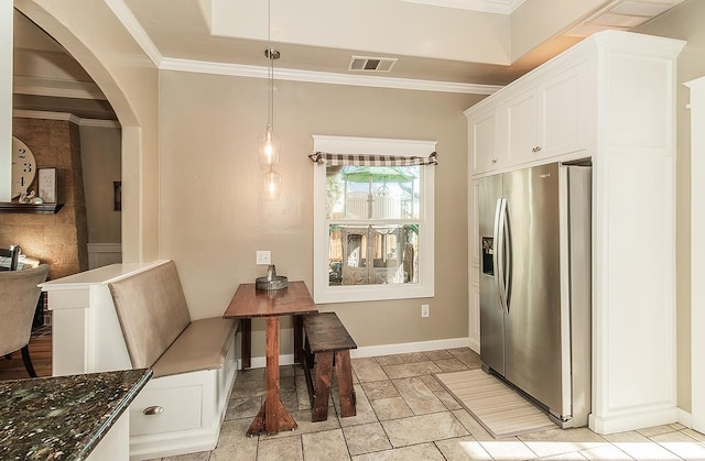 kitchen with arched walkways, white cabinetry, crown molding, and stainless steel fridge with ice dispenser