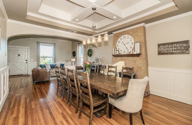 dining room featuring arched walkways, coffered ceiling, wood finished floors, visible vents, and wainscoting