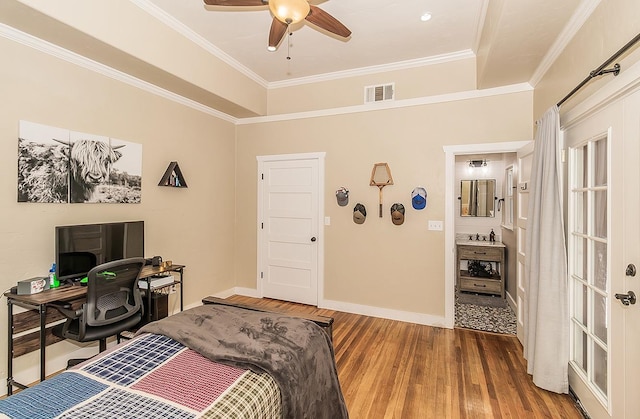 bedroom with a sink, wood finished floors, visible vents, baseboards, and ornamental molding