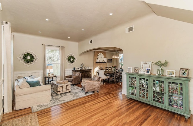 living area with arched walkways, wainscoting, visible vents, and wood finished floors