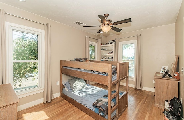 bedroom with light wood-type flooring, visible vents, ceiling fan, and baseboards