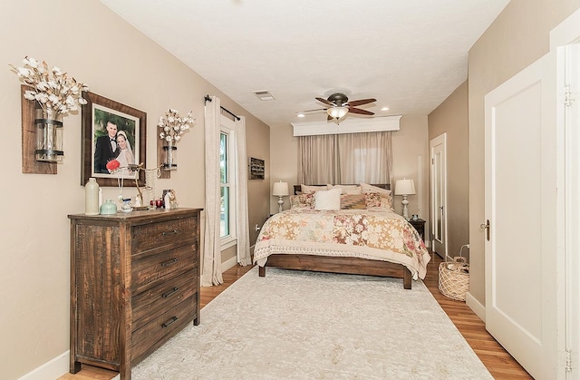 bedroom with light wood-type flooring, baseboards, visible vents, and ceiling fan