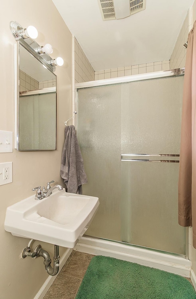 bathroom with visible vents, a sink, and a shower stall