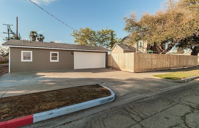 garage with concrete driveway and fence