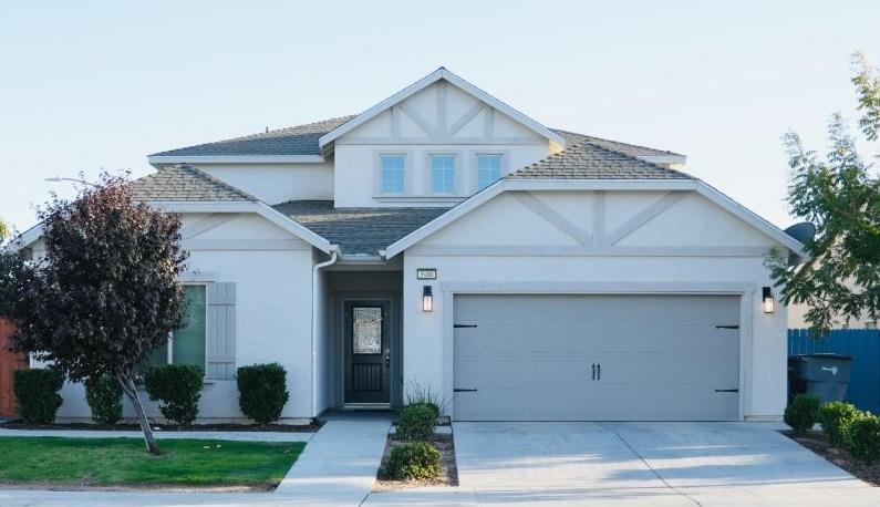 view of front of home with driveway, a shingled roof, an attached garage, fence, and stucco siding