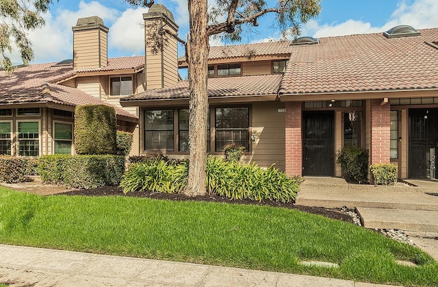 exterior space featuring brick siding, a front lawn, and a tile roof