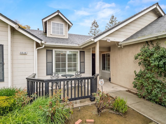 property entrance with a shingled roof and stucco siding