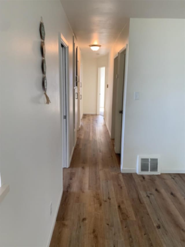 corridor featuring light wood-style floors, visible vents, and baseboards