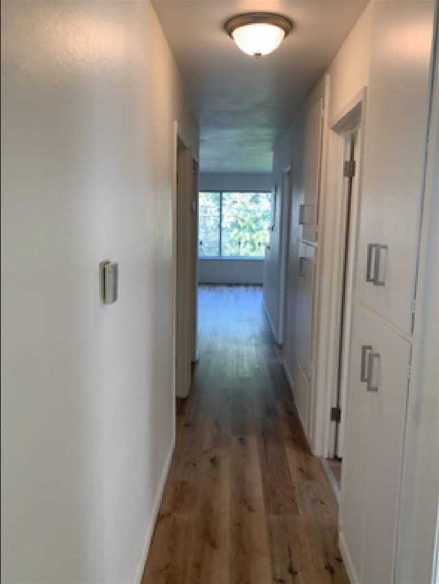 corridor with light wood-type flooring and baseboards