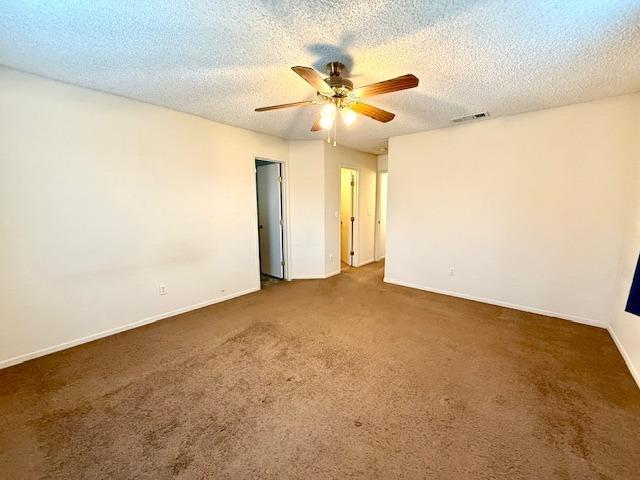 spare room with visible vents, carpet flooring, ceiling fan, a textured ceiling, and baseboards