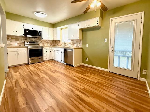 kitchen with light wood-style floors, tasteful backsplash, appliances with stainless steel finishes, and white cabinets