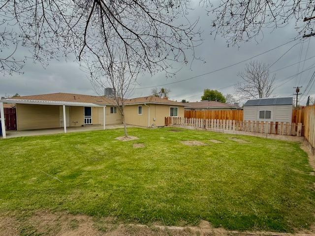 back of house featuring a patio area, fence, an outdoor structure, and a yard