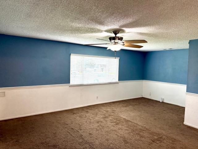 unfurnished room with ceiling fan, a textured ceiling, and carpet flooring