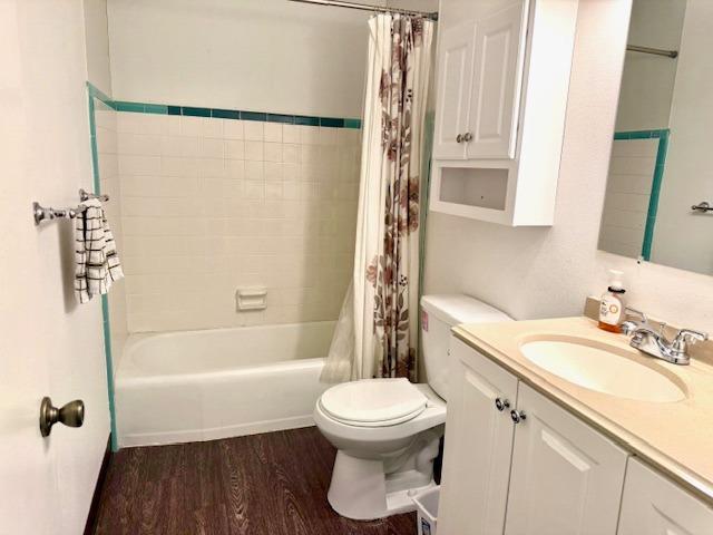 full bathroom featuring shower / bath combination with curtain, vanity, toilet, and wood finished floors