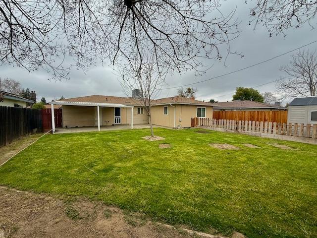 rear view of house featuring a fenced backyard, a lawn, and a patio