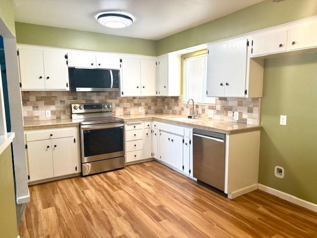 kitchen with white cabinets, appliances with stainless steel finishes, light countertops, and a sink