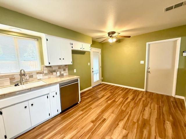 kitchen with tile countertops, visible vents, white cabinetry, a sink, and dishwasher