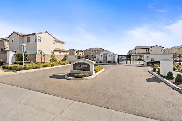 view of street with a gate, a residential view, a gated entry, and curbs