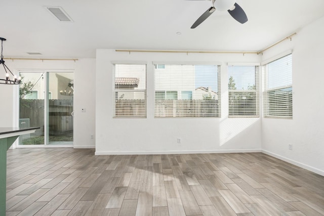 unfurnished sunroom featuring visible vents and ceiling fan with notable chandelier