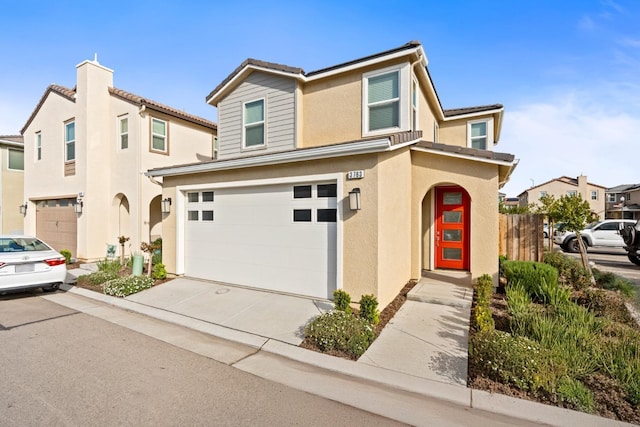 traditional-style home featuring concrete driveway, fence, an attached garage, and stucco siding