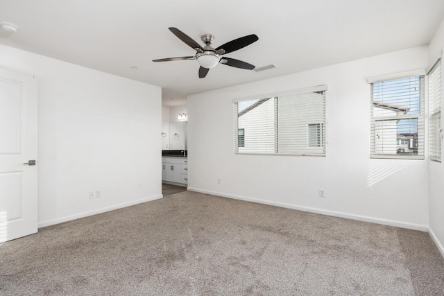 carpeted spare room with a wealth of natural light, a ceiling fan, visible vents, and baseboards