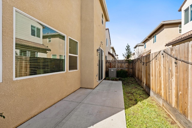 view of side of property with fence private yard, a patio area, cooling unit, and stucco siding