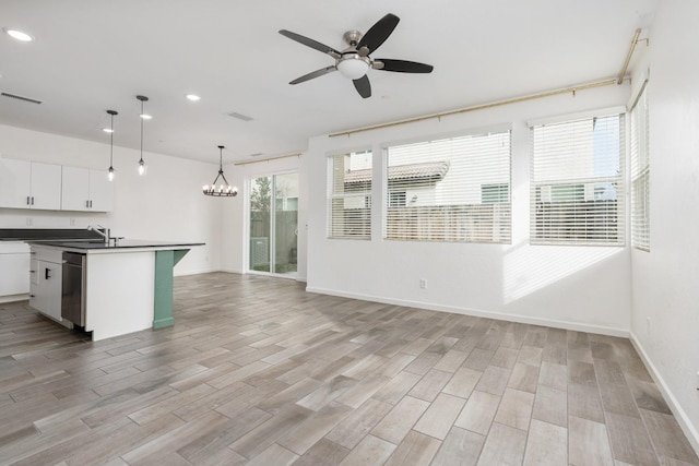 kitchen with ceiling fan with notable chandelier, white cabinetry, light wood-style floors, dishwasher, and dark countertops