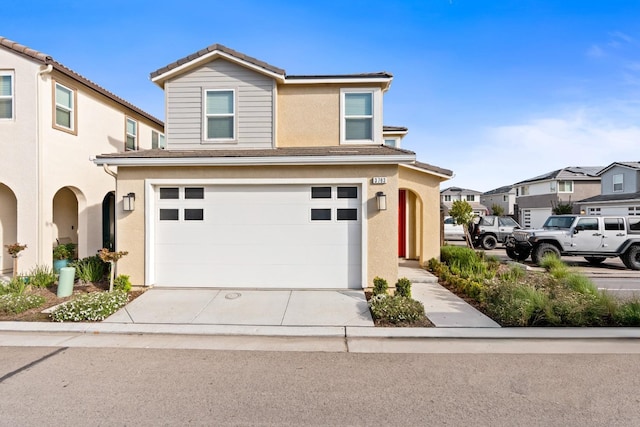 traditional home featuring a garage, concrete driveway, a residential view, a tiled roof, and stucco siding