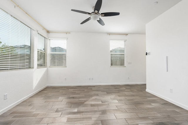 empty room with baseboards, ceiling fan, and wood tiled floor