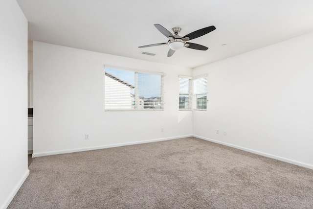 carpeted empty room with a ceiling fan, visible vents, and baseboards