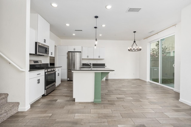 kitchen featuring stainless steel appliances, dark countertops, white cabinetry, and visible vents