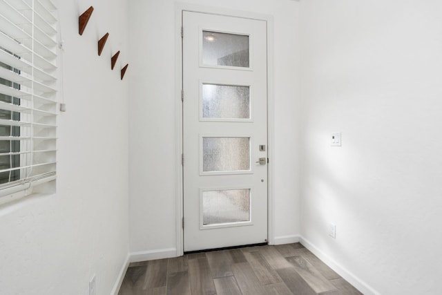 doorway to outside featuring baseboards and wood finished floors