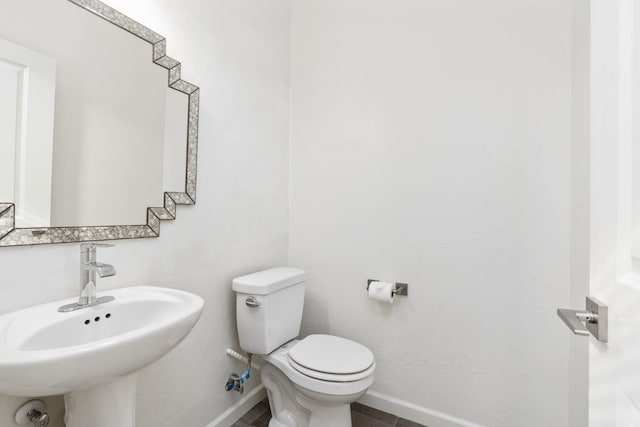 half bath featuring a sink, toilet, and baseboards