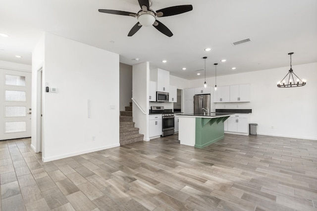 kitchen with light wood-style flooring, visible vents, open floor plan, appliances with stainless steel finishes, and dark countertops