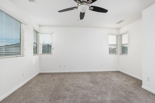 empty room with ceiling fan, carpet flooring, visible vents, and baseboards