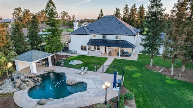 back of property at dusk featuring a standing seam roof, a patio, a lawn, and fence