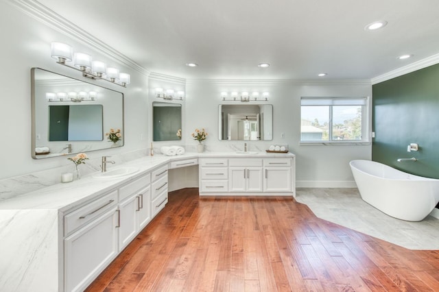 bathroom with a freestanding tub, recessed lighting, vanity, wood-type flooring, and crown molding