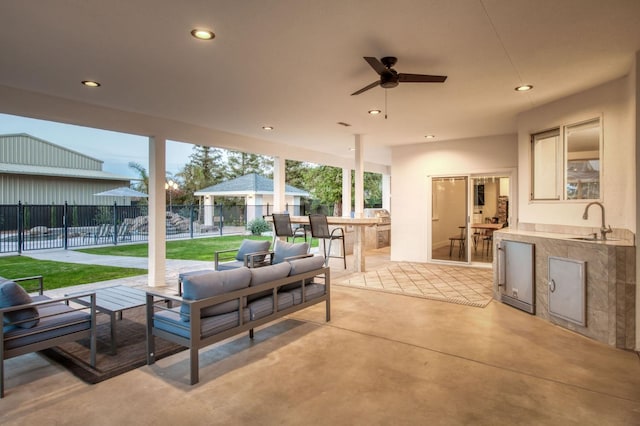 view of patio with area for grilling, an outdoor hangout area, fence, outdoor wet bar, and a sink